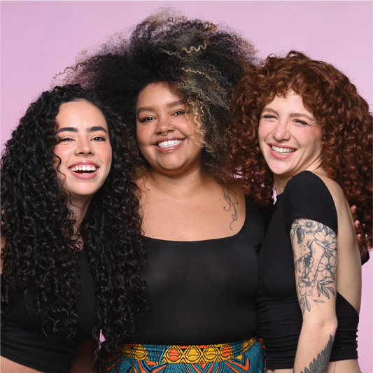Tres mujeres con distintos tipos de rizos sonriendo juntas